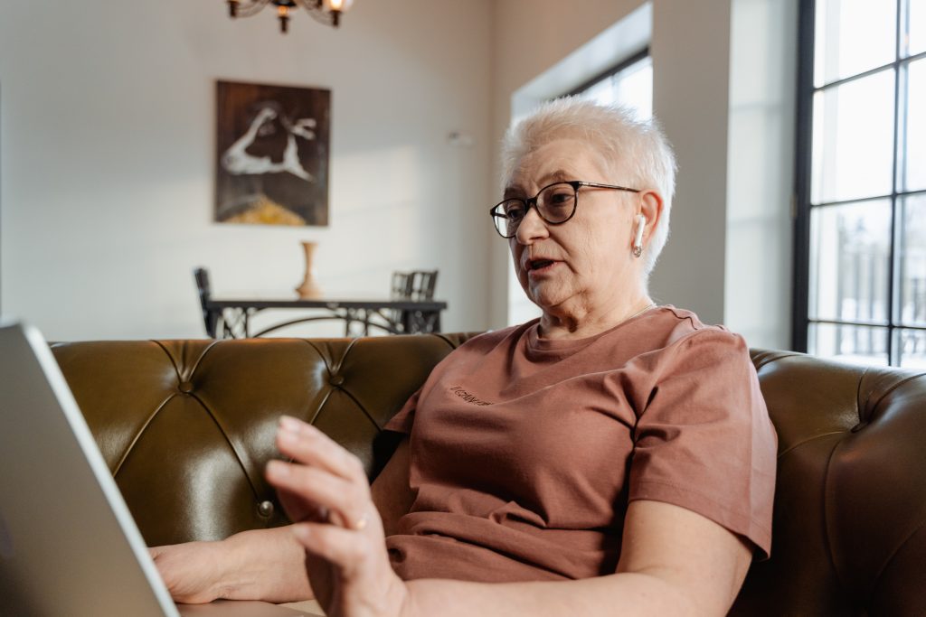 grandmother sitting on a couch in her living room on the laptop