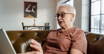 grandmother sitting on a couch in her living room on the laptop